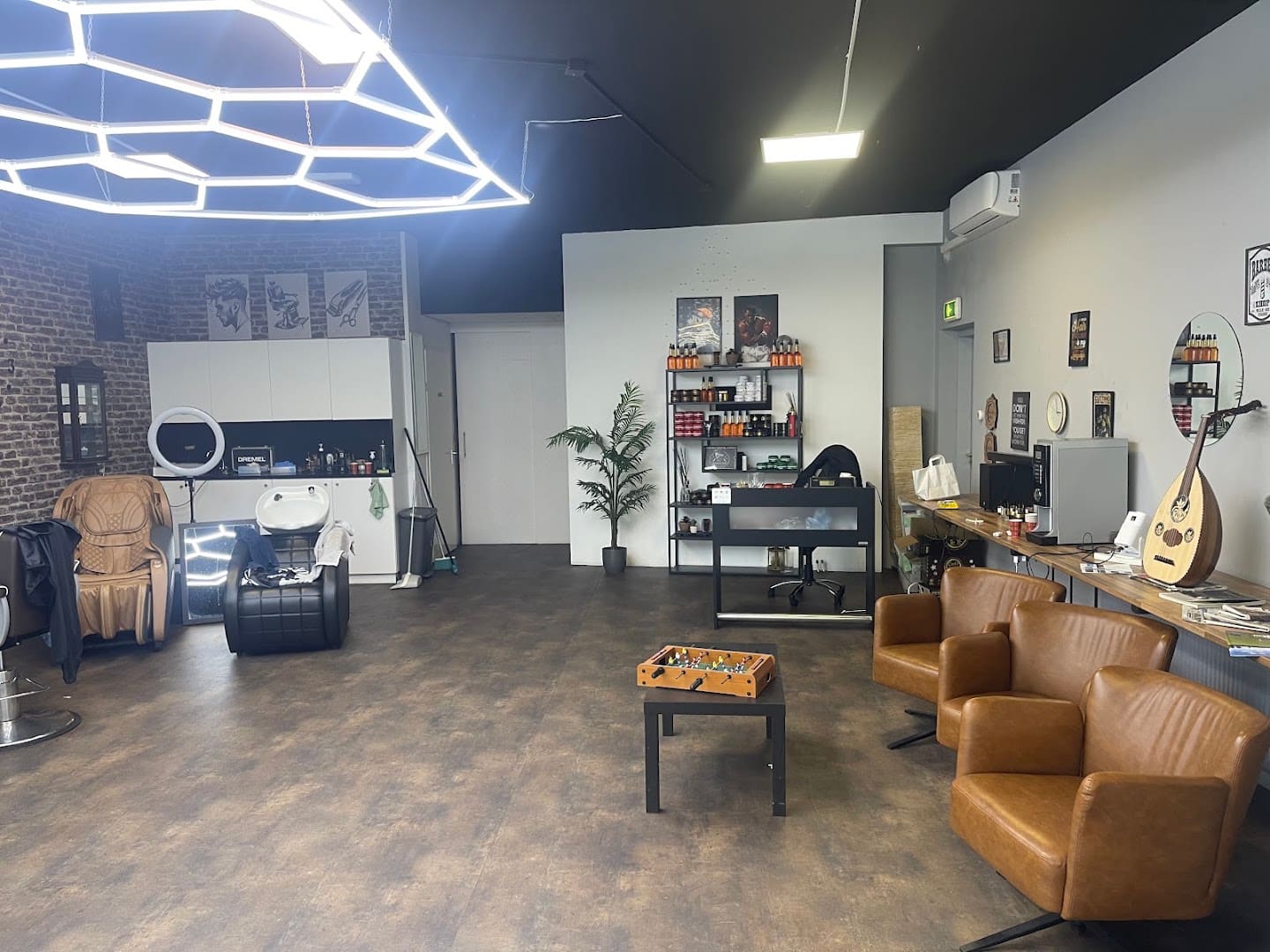 De wachtruimte bij Herenkapper Samer met tafelvoetbal, lounge-stoelen en een bakstenen muur
