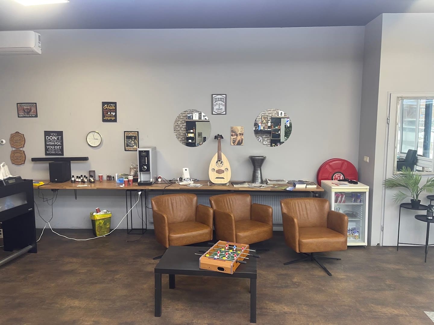 Zithoek met leren fauteuils en muziekinstrumenten aan de wand bij Herenkapper Samer